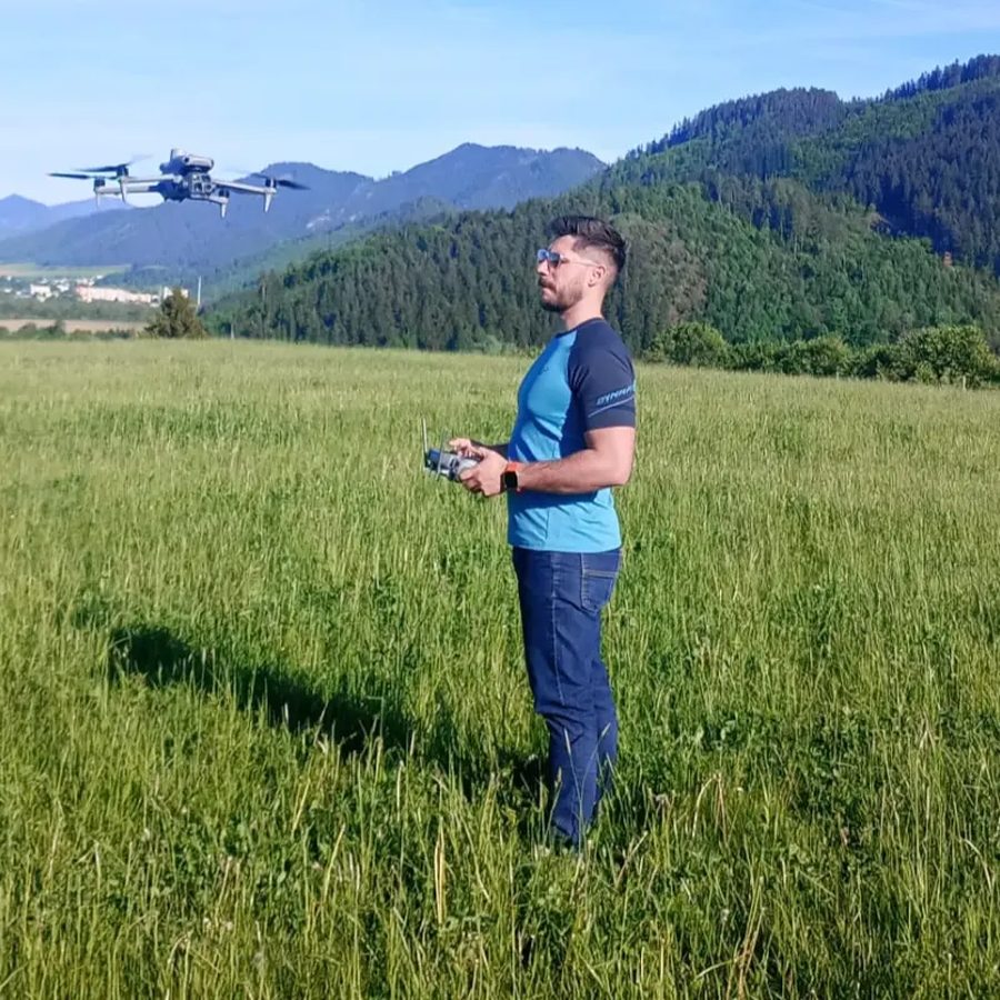 Pilot s ovládačom a dron nad lúkou pri Liptovskom Mikuláši